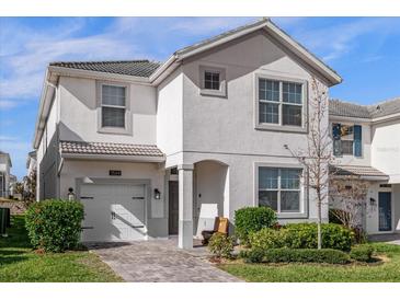 Two-story house with gray exterior, two-car garage, and landscaped yard at 1564 Flange Dr, Davenport, FL 33896