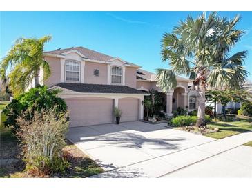 Two-story house with three-car garage, landscaping, and palm trees at 437 Prestwick Dr, Davenport, FL 33897