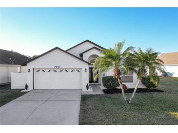 White house with a two-car garage and palm trees in the front yard at 7921 Golden Pond Cir, Kissimmee, FL 34747