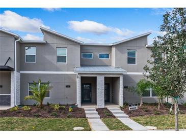 Two-story townhome with gray exterior, landscaping, and two-car driveway at 1060 Leader St, Davenport, FL 33896