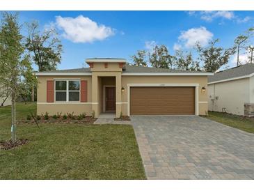 Tan house with brown garage door, landscaping, and paved driveway at 1244 White Ash Loop, Deland, FL 32720