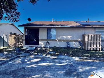 Tan house with a brown roof and solar panels, featuring a fenced yard at 1332 Azalea Way, Winter Garden, FL 34787