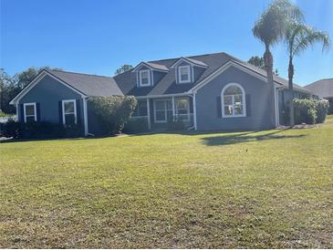 Gray house with a large yard, palm trees, and a driveway at 1901 Griff Wood Ct, Saint Cloud, FL 34772