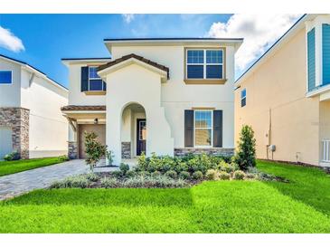 Two-story house with a modern design, landscaped lawn, and a paved driveway at 1919 Tropical Palms Cir, Kissimmee, FL 34747