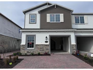 Two-story home with stone accents and a paved driveway at 5100 Rain Shadow Dr, Saint Cloud, FL 34772