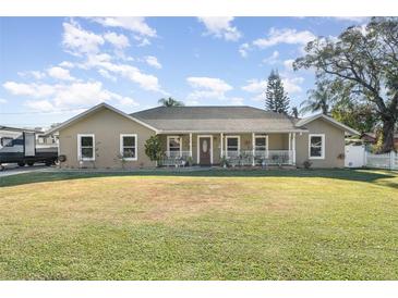 Tan house with white trim, front porch, and grassy lawn at 5572 Myakka Ave, Intercession City, FL 33848