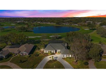 Stunning aerial view of a home with a circular driveway overlooking a serene lake and lush green golf course at 8513 Bay Hill Blvd, Orlando, FL 32819