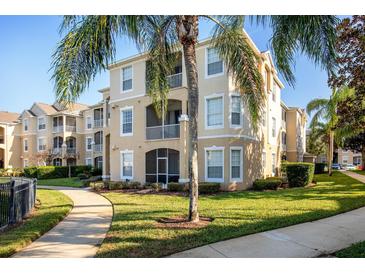 Tan building exterior with palm trees and landscaped grounds at 2300 Butterfly Palm Way # 205, Kissimmee, FL 34747