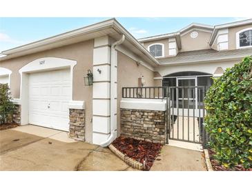 Tan two-story townhome with white garage door and landscaping at 3237 River Branch, Kissimmee, FL 34741