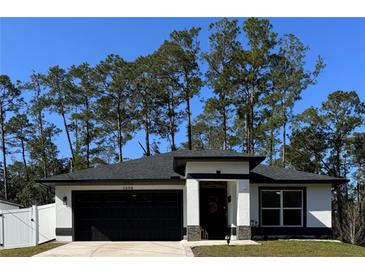 White house with black roof and garage, nestled among tall pine trees at 1490 11Th Ave, Deland, FL 32724