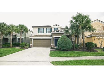 Two-story house with green exterior, attached garage, and manicured lawn at 5290 Wildwood Way, Davenport, FL 33837