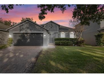 Gray house with 2-car garage, manicured lawn, and brick driveway at 1449 Ashdown Ct, Sanford, FL 32771