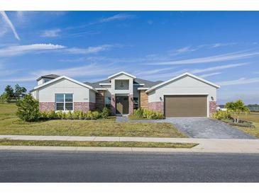 Single-story home with a two-car garage and landscaped front yard at 208 Snowy Orchid Way, Lake Alfred, FL 33850