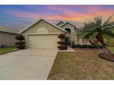 Tan house with a two-car garage, landscaping, and a palm tree at 2368 Monaco Cove Cir, Orlando, FL 32825