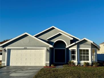 Newly constructed home with gray exterior, white garage door, and landscaping at 2413 Rock Ct, Poinciana, FL 34759