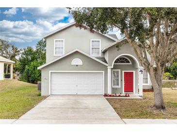 Two-story house with a gray facade, red door, and a two-car garage at 587 Bluff Pass Dr, Eustis, FL 32726