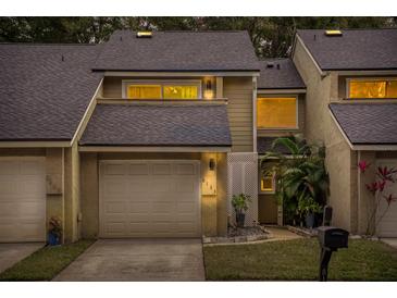 Tan two-story townhome with a white garage door and landscaping at 8133 Citrus Chase Dr, Orlando, FL 32836