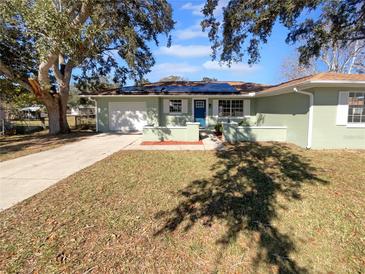 Newly renovated light green house with a blue door, solar panels, and a well-maintained lawn at 14912 Sw 35Th Cir, Ocala, FL 34473