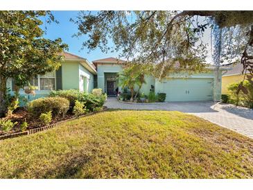 Light green house with a paved driveway and mature landscaping at 300 Sorrento Rd, Poinciana, FL 34759