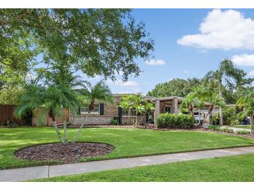 Brick ranch home with landscaped lawn, palm trees, and covered entry at 322 Apopka St, Winter Garden, FL 34787