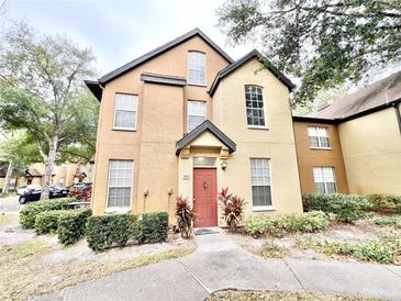 Two-story townhome with orange exterior, red door, and landscaping at 6356 Raleigh St # 1503, Orlando, FL 32835