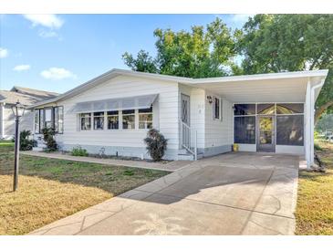 White single-wide manufactured home with carport and landscaped yard at 712 Jason Dr, Lady Lake, FL 32159