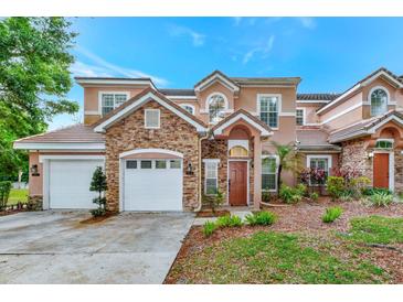 Two-story stucco home with stone accents, two-car garage, and landscaped yard at 7615 Bay Port Rd # 36, Orlando, FL 32819