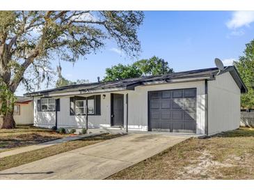 Updated single story home with gray garage door and light colored siding at 2952 Elkcam Blvd, Deltona, FL 32738