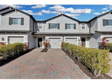 Charming townhomes with brick driveways, attached garages, and well-manicured landscaping under a bright blue sky at 12067 White Wave Pt, Orlando, FL 32828