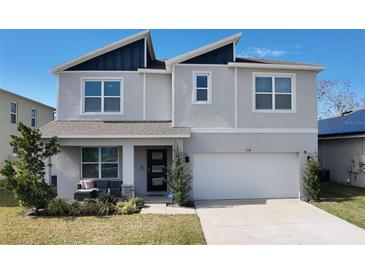 Two-story house with gray siding, dark gray roof accents, and a two-car garage at 236 Talisi Loop, St Cloud, FL 34771