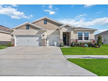 Two-story house with a three-car garage and landscaped yard at 6922 Audobon Osprey Cv, Harmony, FL 34773