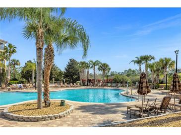 Large community pool with comfortable lounge chairs and palm trees at 8801 Worldquest Blvd, Orlando, FL 32821