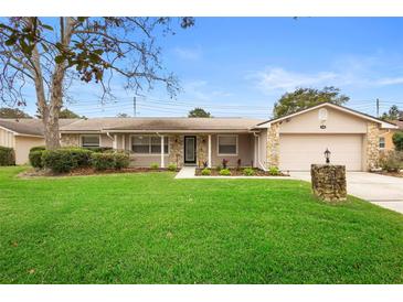 Tan house with stone accents, landscaped lawn, and a two-car garage at 1266 Juliana Pl, Orlando, FL 32807