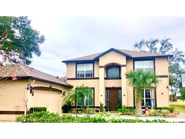 Two-story house with tan walls, brown accents, and a landscaped yard at 1318 Lucky Pennie Way, Apopka, FL 32712