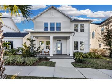 Two-story white house with a front porch and landscaped yard at 210 Hammock Preserve Loop, Winter Garden, FL 34787