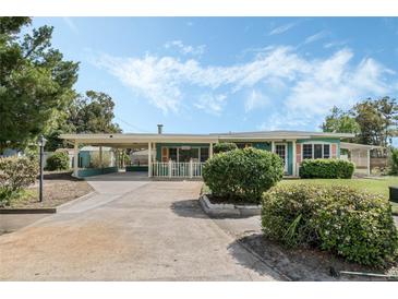 Charming home with a covered porch, lush landscaping, and a spacious carport on a sunny day at 213 Oakland Ave, Sanford, FL 32773