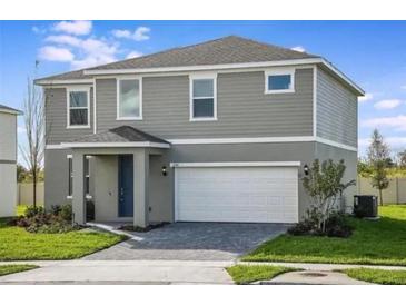 Two-story house with gray siding, a white garage door, and a well-manicured lawn at 267 Bottle Brush Dr, Haines City, FL 33844