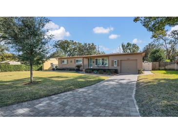 Tan house with a paved driveway and landscaped lawn at 3020 Nancy St, Orlando, FL 32806