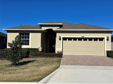 Tan one-story house with two-car garage and landscaped yard at 3855 Serena Ln, Clermont, FL 34711