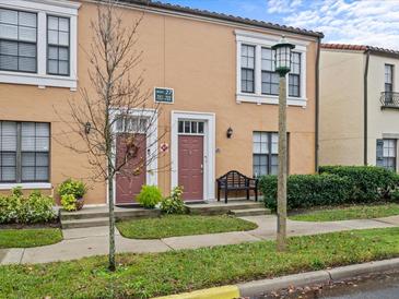 Tan two-story townhome with a red door, landscaping, and a bench at 715 Siena Palm Dr, Celebration, FL 34747