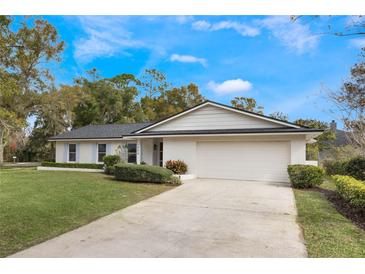 Charming single story home with a manicured lawn, beautiful trees, a 2-car garage, and freshly painted brick at 7884 Broken Arrow Trl, Winter Park, FL 32792