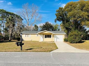 Cute yellow house with a white garage door and landscaped lawn at 8429 Sw 105Th Pl, Ocala, FL 34481