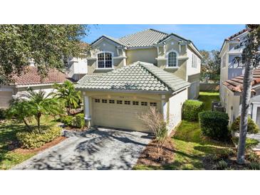 Beige two-story home featuring a tile roof, two-car garage, and well-manicured front lawn at 9132 Via Bella Notte, Orlando, FL 32836