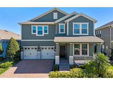 Two-story house with gray siding, white trim, and a brick driveway at 9511 Nautique Ln, Winter Garden, FL 34787