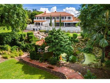 Serene backyard with gazebo, pond, and brick pathway. Lush landscaping surrounds the property at 11148 Lane Park Rd, Tavares, FL 32778