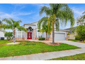 Brick house with red door, palm trees, and a well-manicured lawn at 13656 Crystal River Dr, Orlando, FL 32828