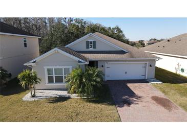 One-story home with gray exterior, brick driveway, and palm trees at 2408 Addison Creek Dr, Kissimmee, FL 34758