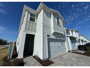 Two-story townhome with gray siding, two-car garage, and a landscaped front yard at 2900 Title St, Kissimmee, FL 34746