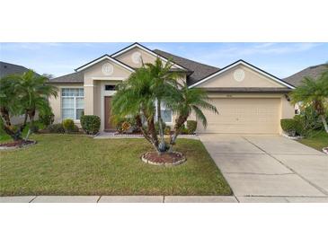 Tan one-story house with palm trees, two-car garage, and landscaped lawn at 2920 River Birch Dr, Kissimmee, FL 34741