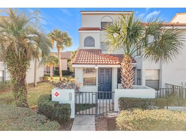 Two-story townhome with a tiled roof, gated entry, and landscaping at 4818 Marks Ter # 385 B2, Orlando, FL 32811